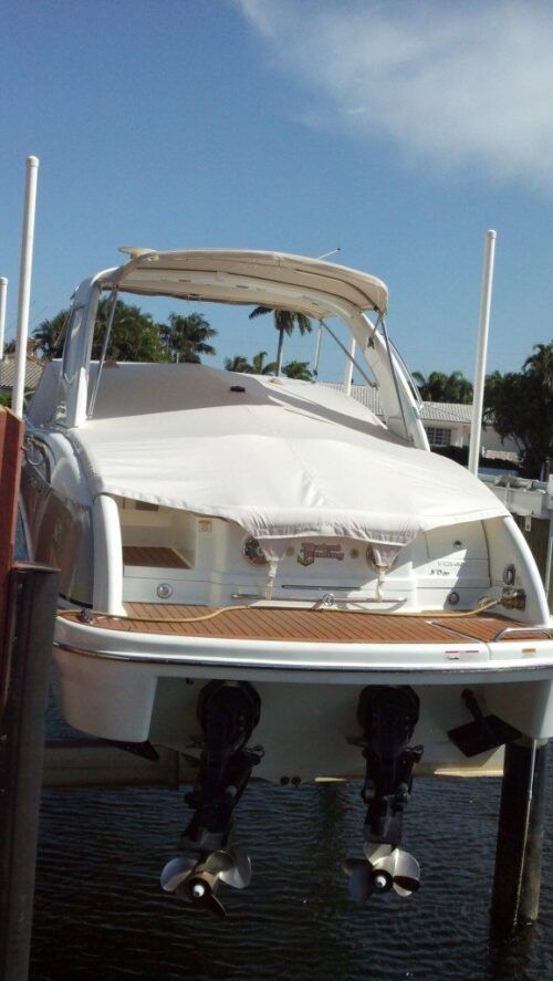 A white boat is docked at a dock in the water.