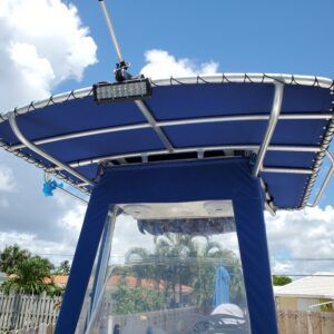 A boat with a blue roof is parked in front of a house.