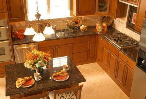 Warm kitchen with wood cabinets, dark countertops, and a small island set with plates and a floral centerpiece.