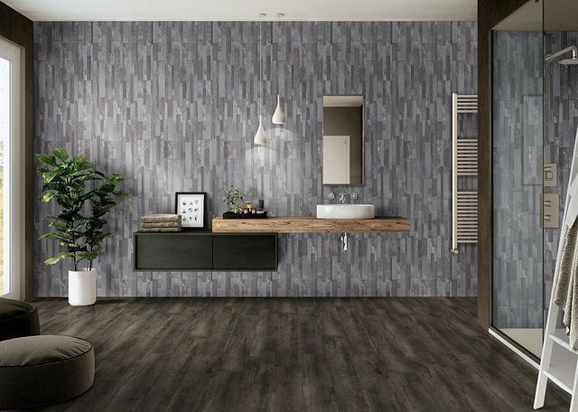 Modern minimalist room with gray patterned walls, dark wood floor, floating desk, mirror, plant, and pendant light