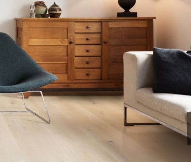 Modern living room with wooden sideboard, blue chair, and light sofa with dark pillows.