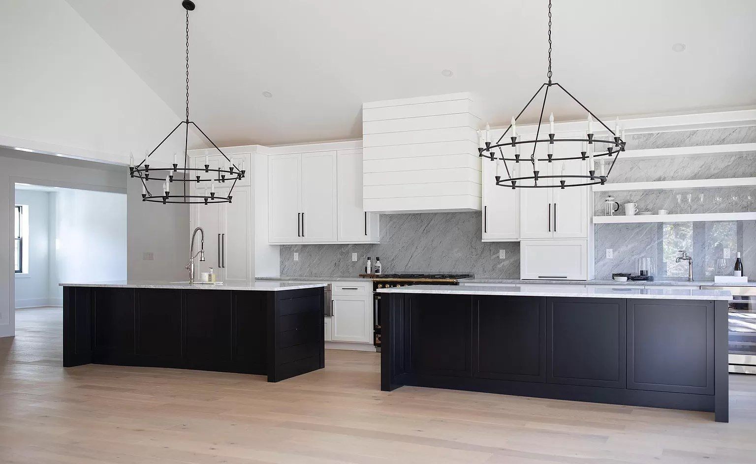 Bright modern kitchen with dark islands, white cabinets, and hanging pendant lights