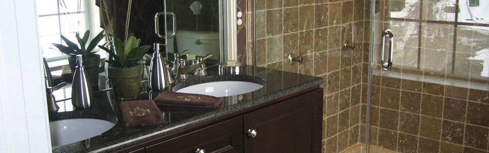 Modern bathroom with a sink, dark vanity, and glass-enclosed shower with brown tile walls