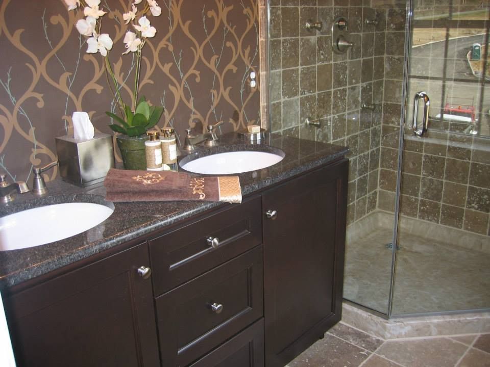 Modern bathroom vanity with double sinks, dark cabinets, and a glass-enclosed shower