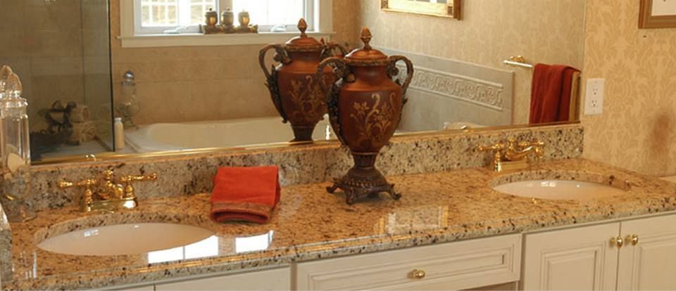 Bathroom vanity with beige granite countertop, oval sink, and two large decorative vases in front of a mirror