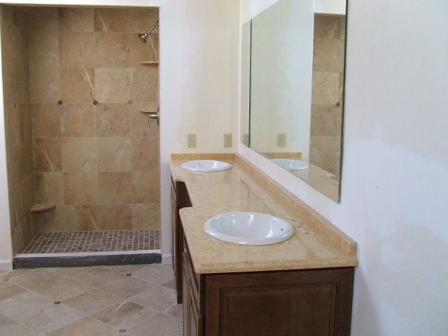 Accessible bathroom vanity with sink, mirror, and tiled shower stall