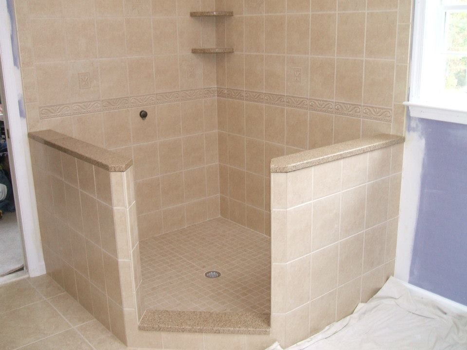 Beige tiled walk-in shower with a curved entry and built-in bench.