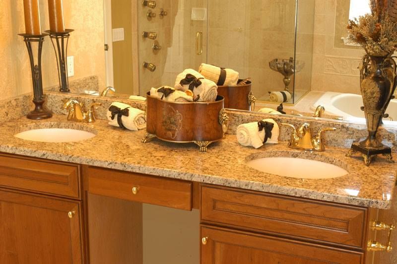Bathroom vanity with granite countertop, double sinks, and decorative soap dispensers and towels