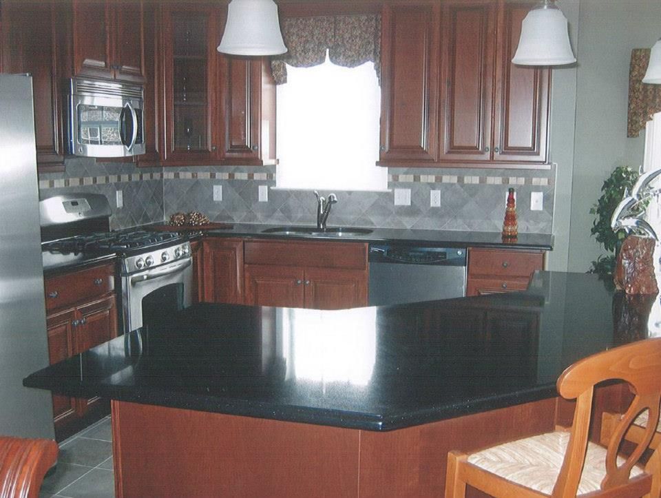 Modern kitchen with dark wood cabinets, black island countertop, and a window above the sink