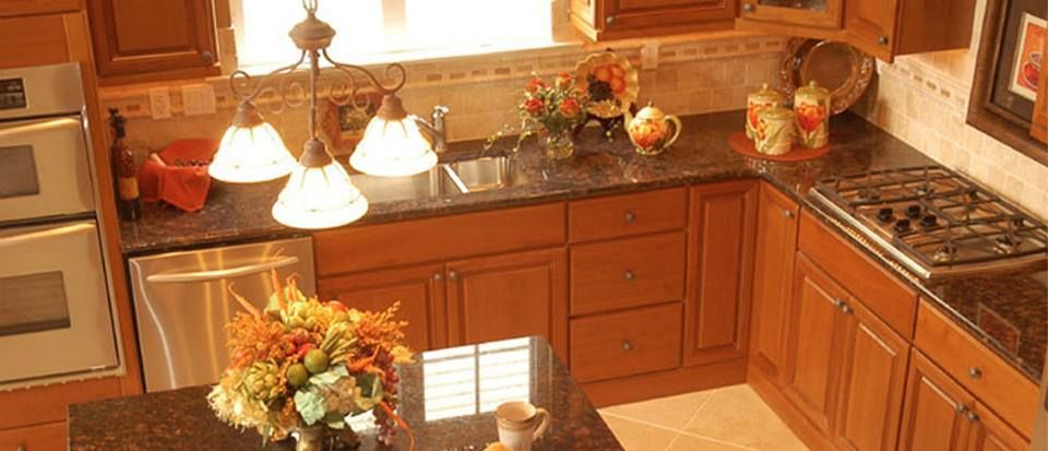 Warm wooden kitchen with cabinets, sink, stove, and a vase of flowers on the counter.