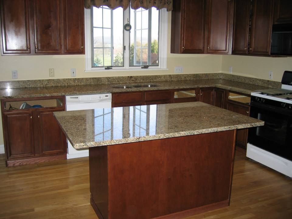 Modern kitchen with dark wood cabinets, granite countertops, center island, and white stove under a window.