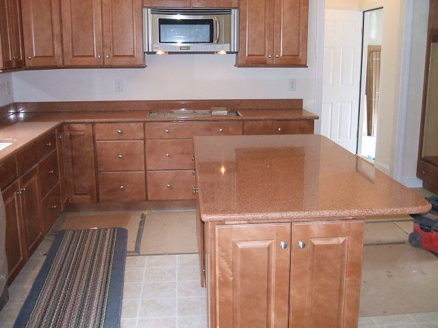Kitchen with wooden cabinets, tiled floor, and a central island with granite countertop