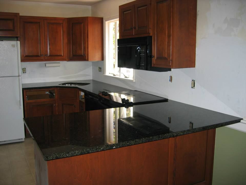 Modern kitchen with dark wood cabinets, black granite island, and white walls