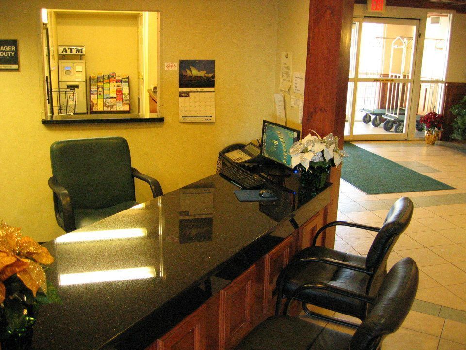Hotel lobby reception desk with black counter, chairs, and yellow walls