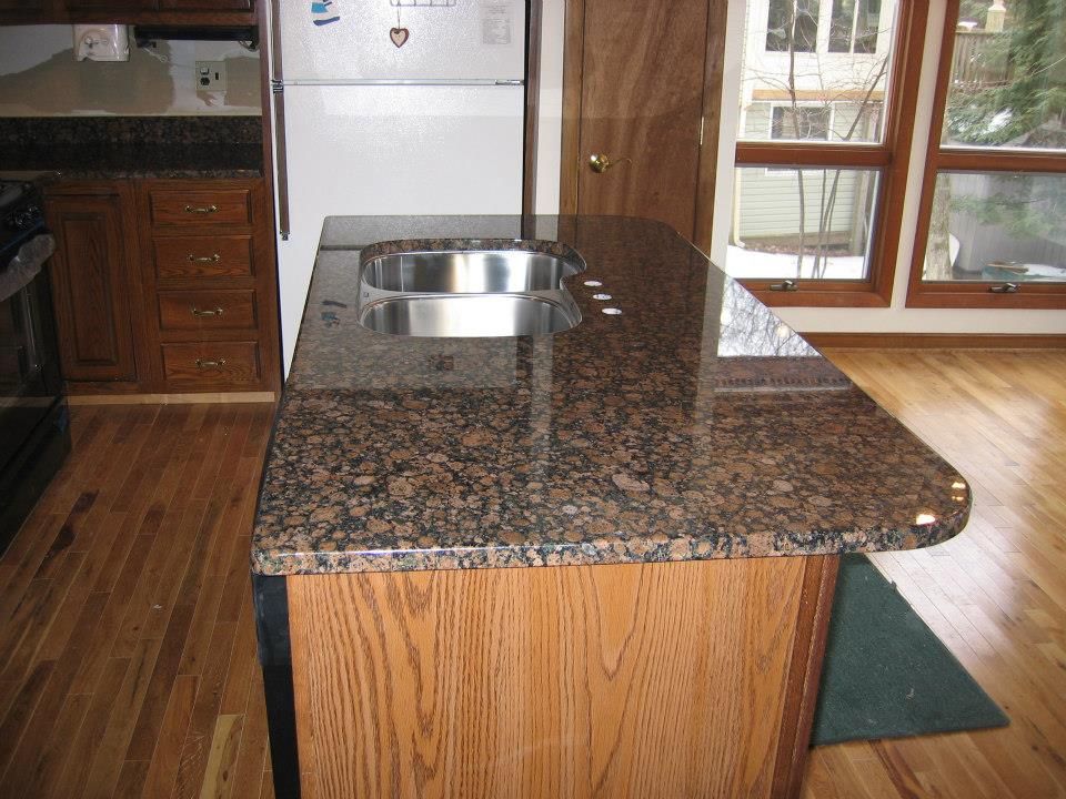 Kitchen island with granite countertop and built-in sink in a wood-finished kitchen