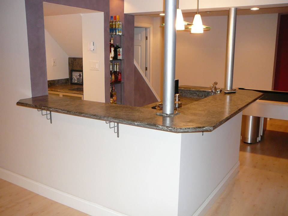 Modern kitchen with tan granite breakfast bar, hanging pendant lights, and light wood floors