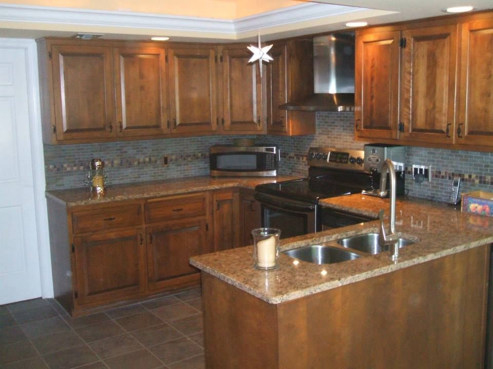 Modern kitchen with wooden cabinets, granite countertops, tiled backsplash, and a central island with sink.