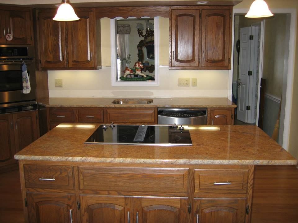 Wooden kitchen with granite island, dark cabinets, and pendant lights over the counter.