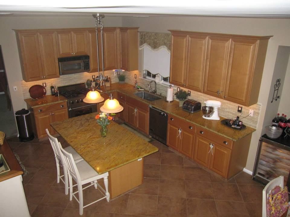 Kitchen with wooden cabinets, tiled floor, island table, and hanging lights viewed from above
