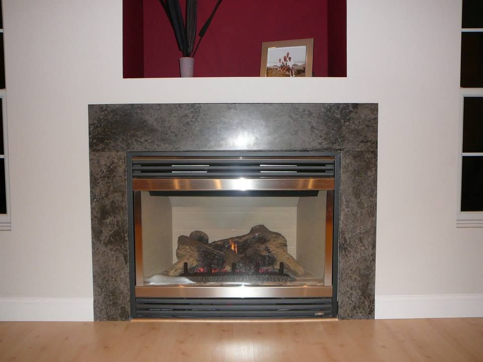 Modern fireplace with glass front, surrounded by gray stone in a living room.