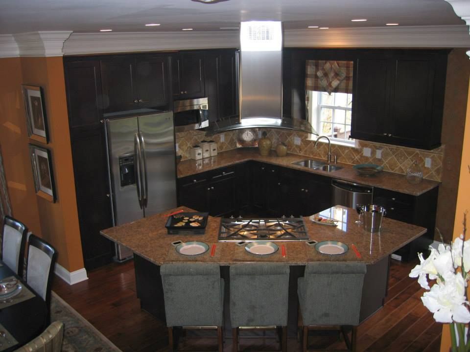 Modern kitchen with dark cabinets, granite island, stainless fridge, and place settings on the counter