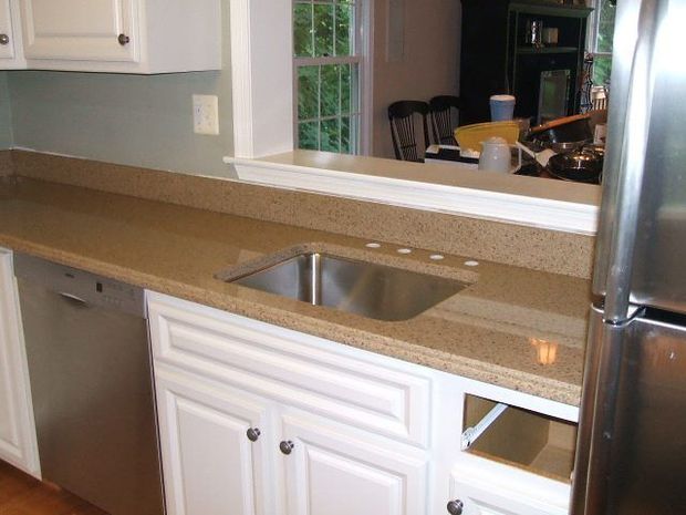 Kitchen counter with tan granite, stainless sink, white cabinets, and a pass-through to a dining area