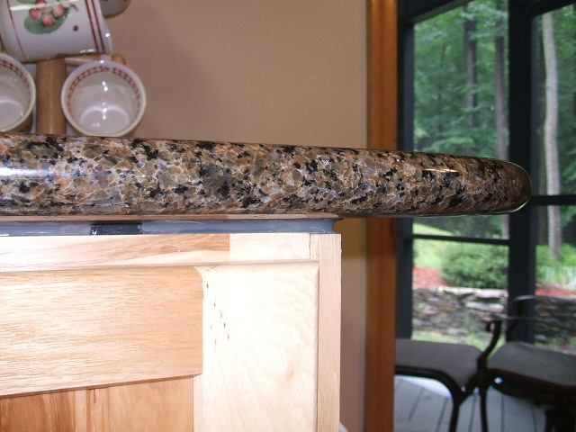 Granite kitchen countertop beside a window, with a mug and plate on the counter and a forest view outside