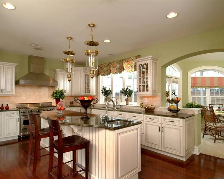 Bright kitchen with white cabinets, granite island, and arched doorway to dining area.