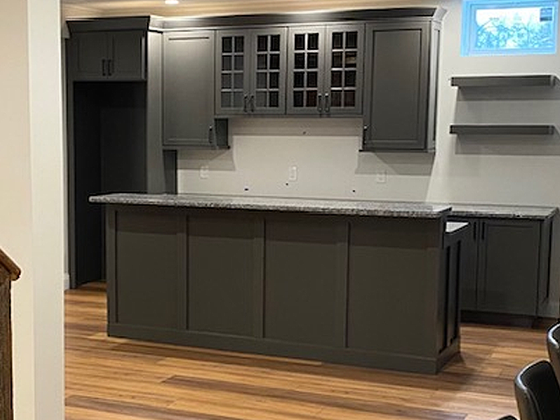 Modern kitchen with dark gray cabinets, island, granite countertops, and hardwood floors