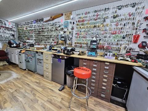 A workshop filled with tools, keys, and equipment displayed on walls and work surfaces.