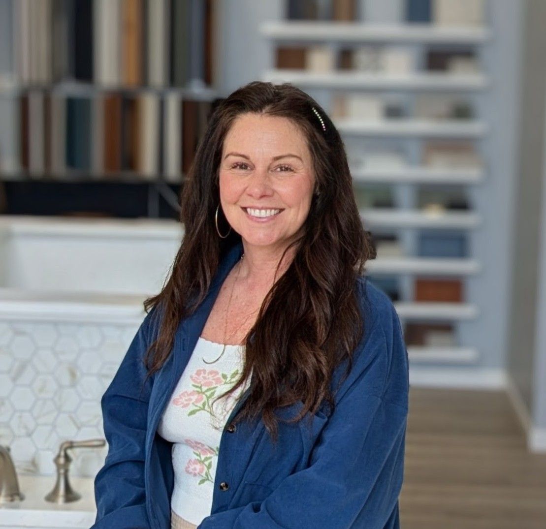 A woman in a blue shirt is smiling in front of a counter