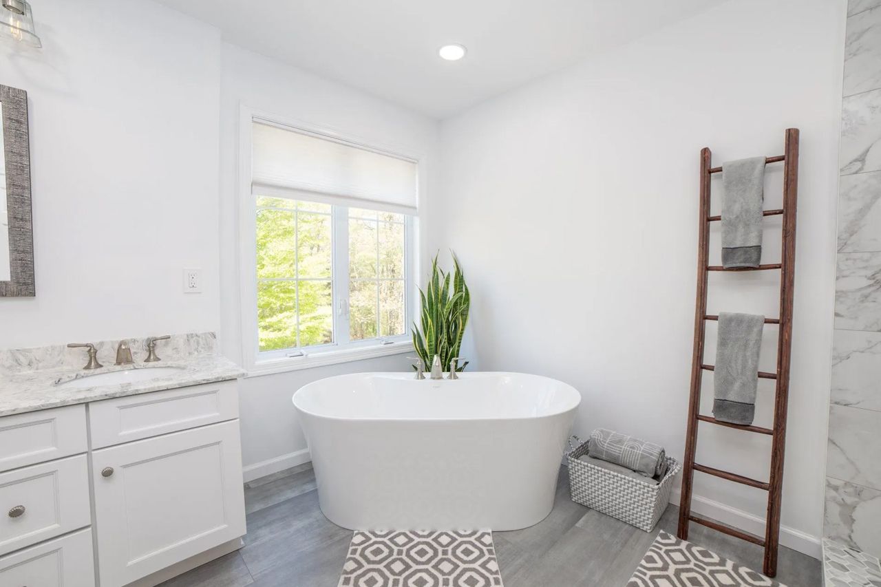A bathroom with a tub, sink, mirror and towel rack.