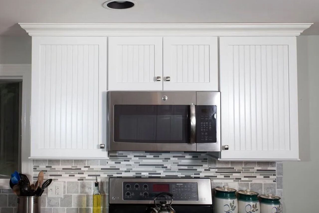 A kitchen with white cabinets and a stainless steel microwave oven
