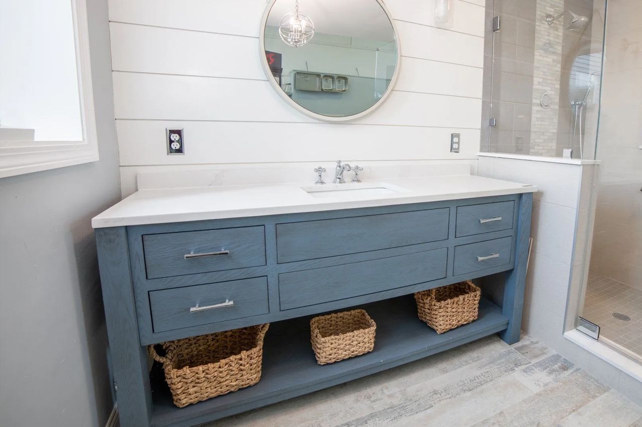 A bathroom with a sink, mirror, and wicker baskets.