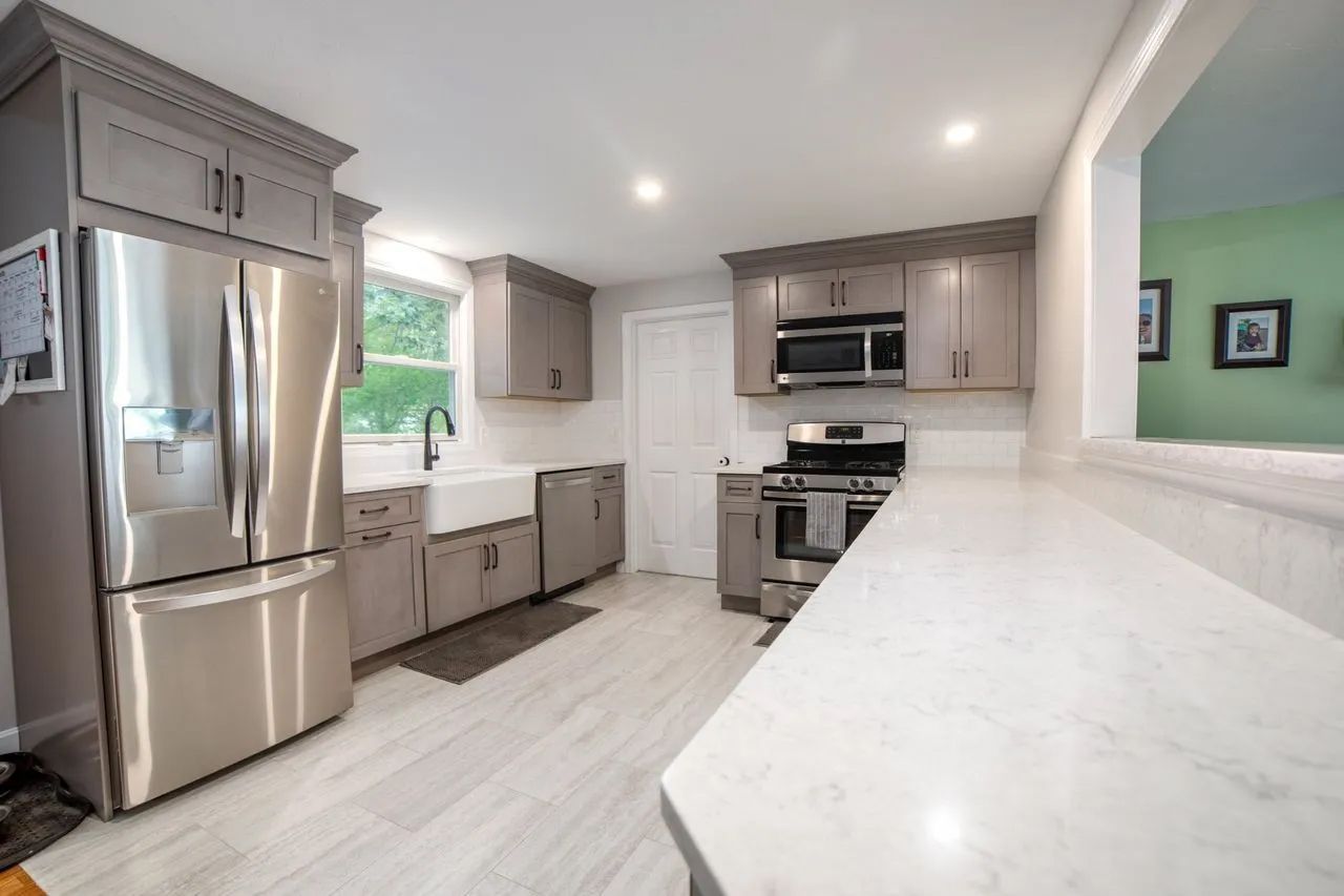 A kitchen with stainless steel appliances and gray cabinets.