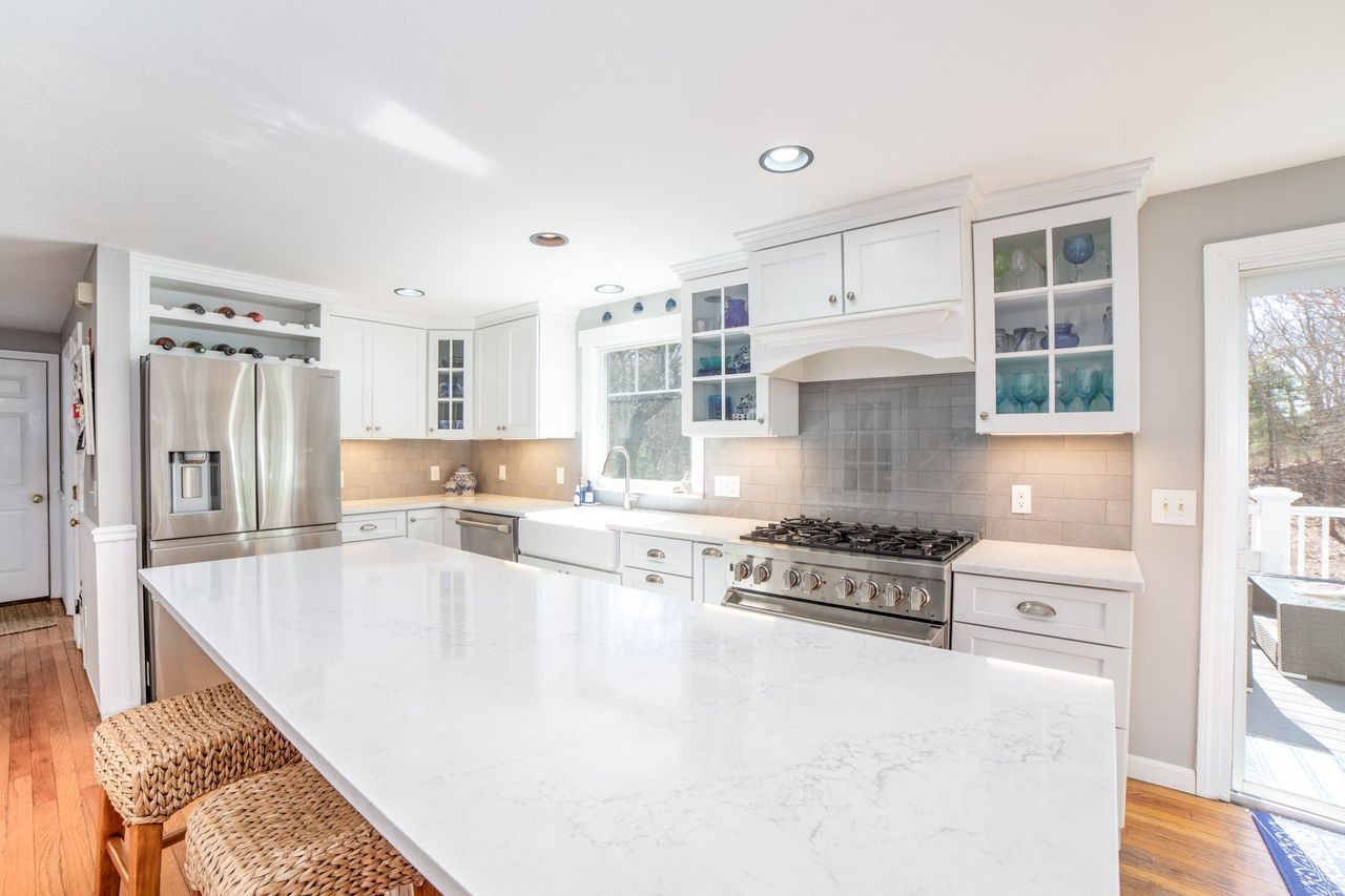 A kitchen with white cabinets , a stove , a refrigerator , and a large island.