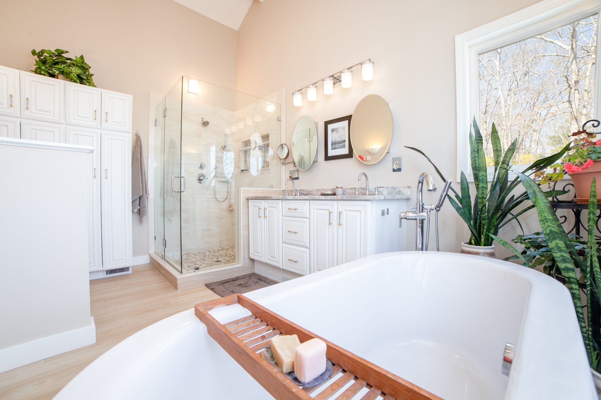 A bathroom with a bathtub , sinks , mirrors and a walk in shower.