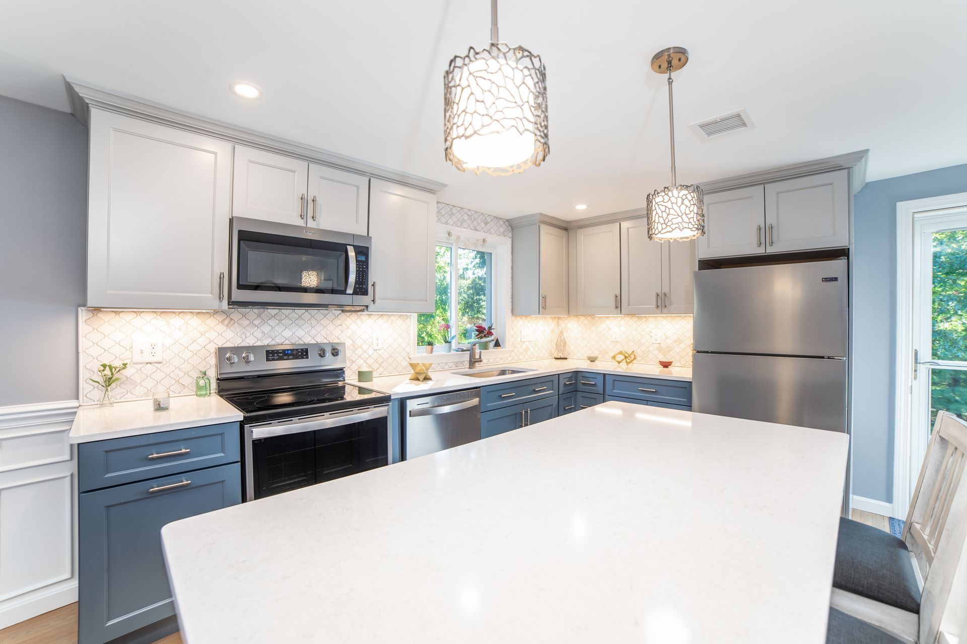 A kitchen with white cabinets, stainless steel appliances, and a large island.