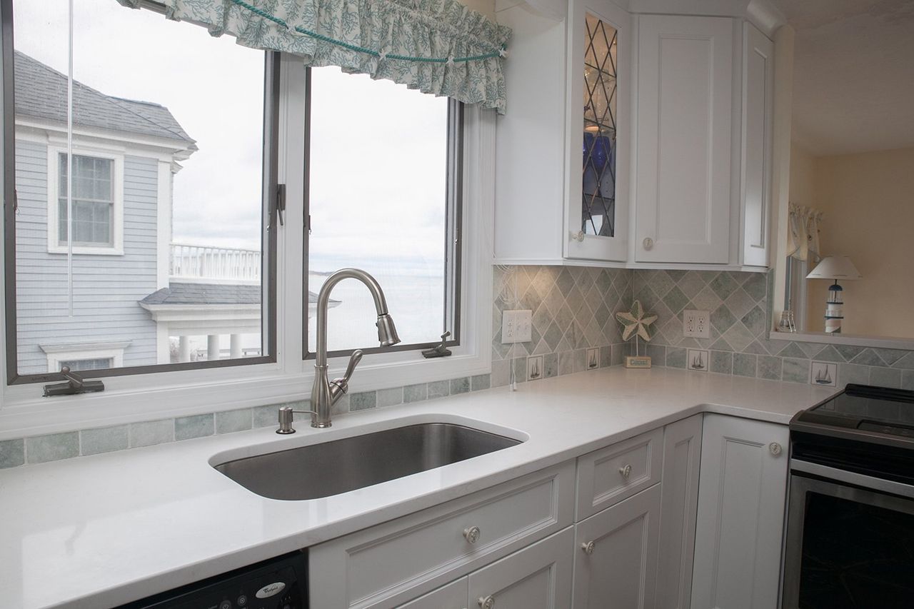 A kitchen with a sink and a window with a view of the ocean.