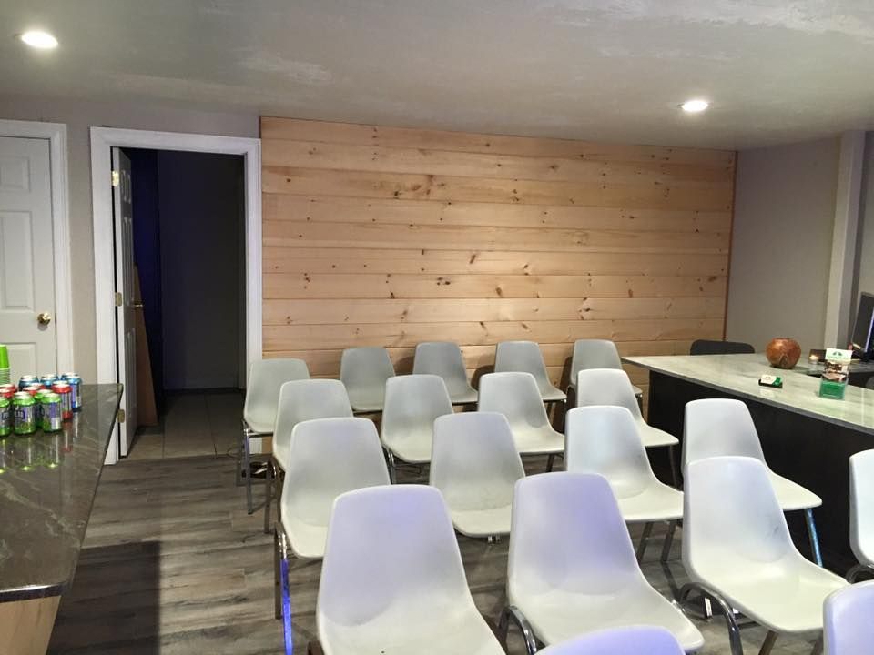 A room with rows of white chairs and a wooden wall.