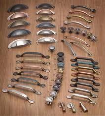 A wooden table topped with a variety of cabinet handles and knobs.