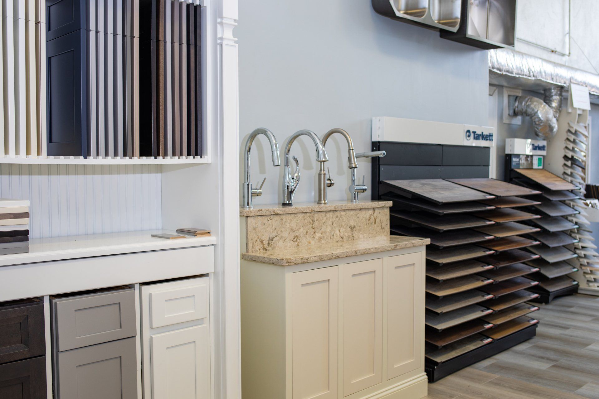 A kitchen showroom with a sink , cabinets , and tiles.