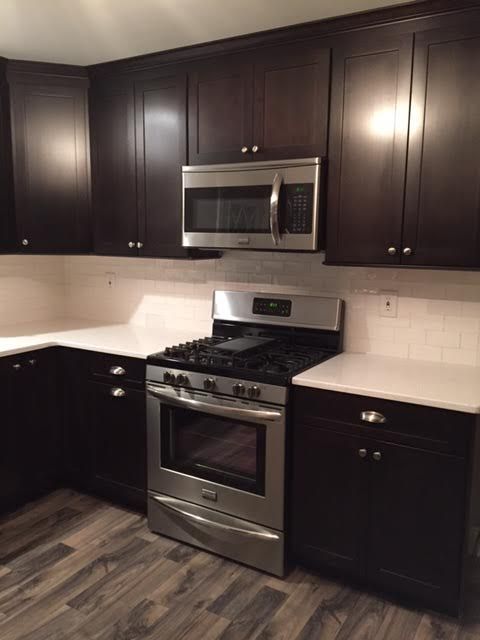 A kitchen with stainless steel appliances and dark cabinets