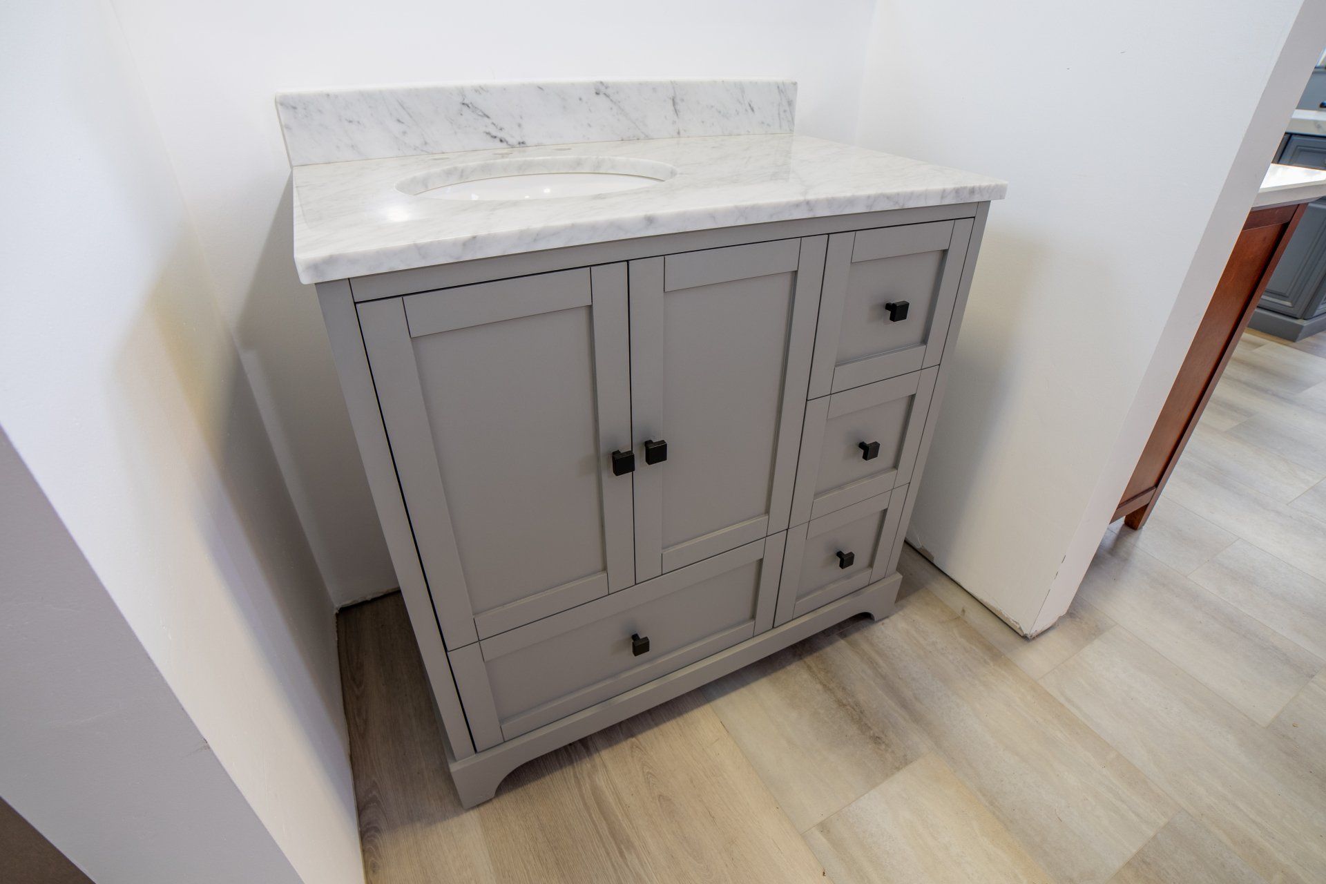 A bathroom vanity with a sink and drawers is sitting on a wooden floor.
