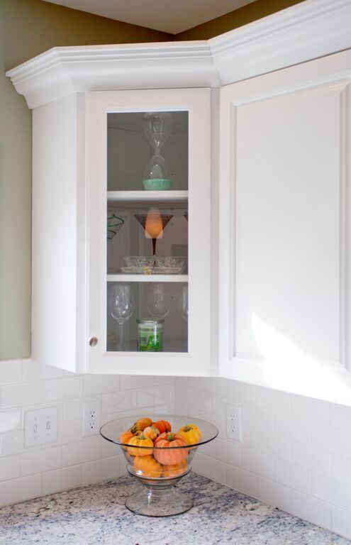 A bowl of fruit sits on a counter next to a glass cabinet.