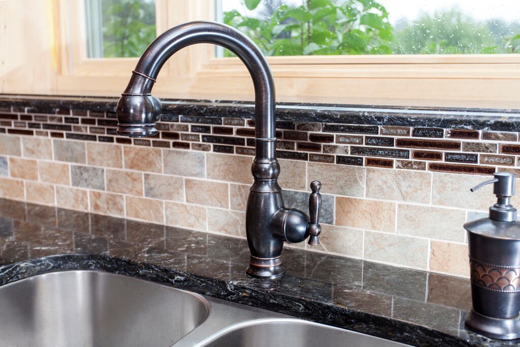 A kitchen sink with a faucet and soap dispenser on the counter.