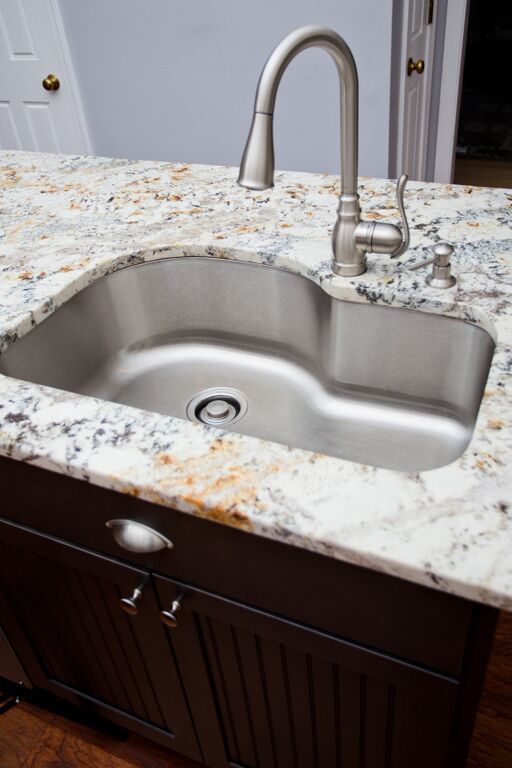 A kitchen sink with a faucet on a granite counter top