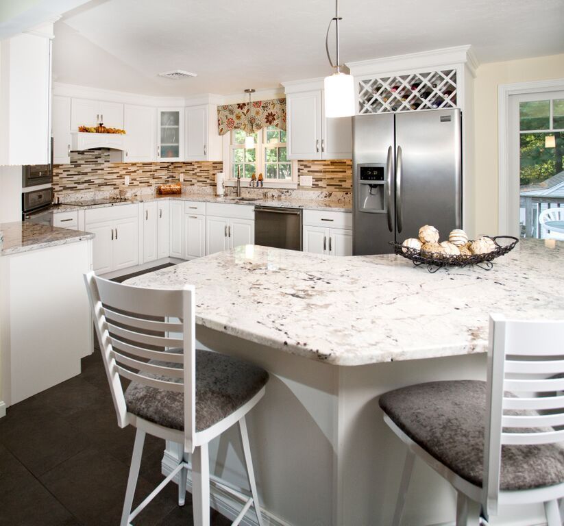 A kitchen with white cabinets and a stainless steel refrigerator