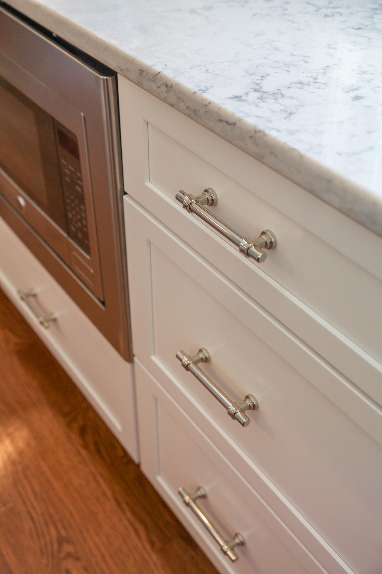A kitchen with white cabinets and a stainless steel microwave oven.
