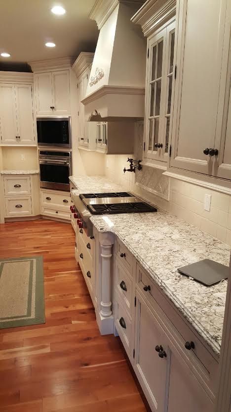 A kitchen with white cabinets and granite counter tops.